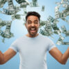 Homem feliz, celebrando algum triunfo, sobre um fundo azul com notas de dinheiro caindo. Conceito de sucesso, riqueza e finanças.