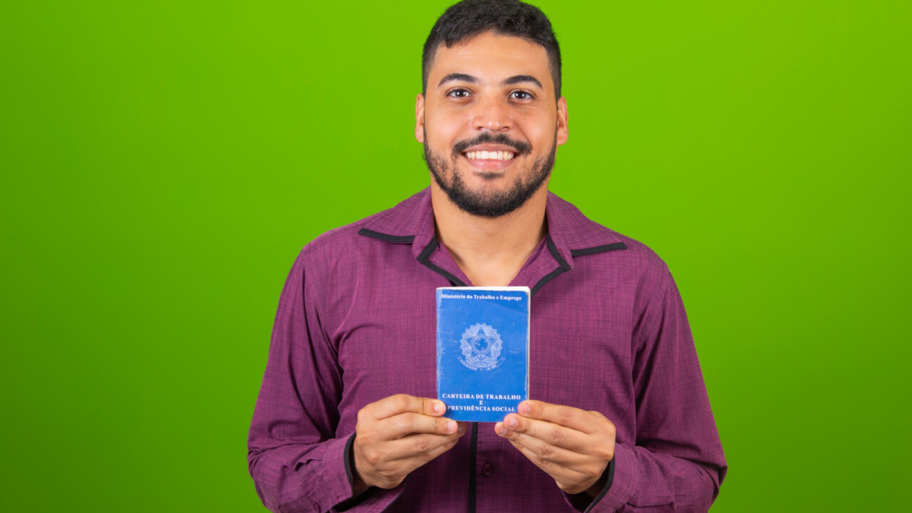 Homem segurando o documento de trabalho e segurança social, (Carteira de Trabalho e Previdência Social).
