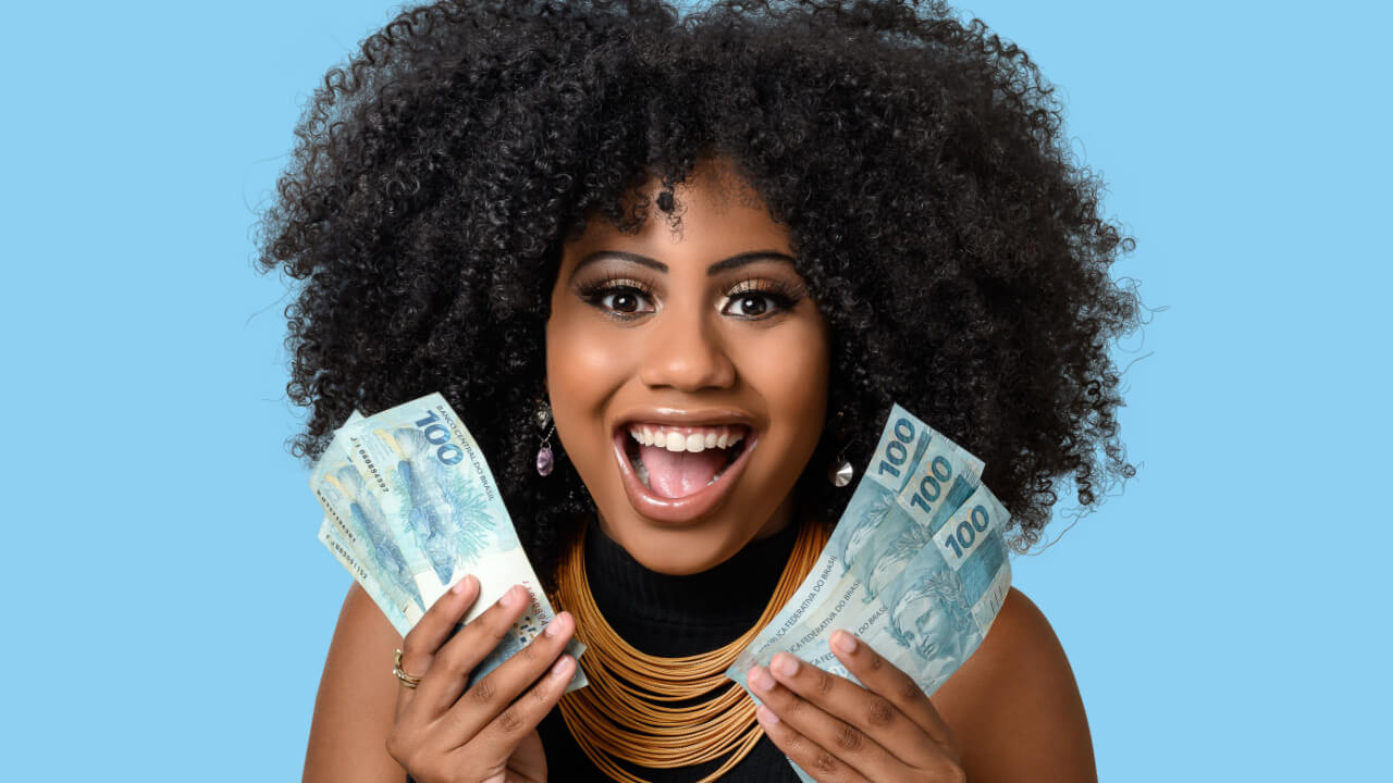 mulher negra com notas de cem reais nas duas mãos em fundo azul