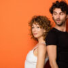 Casal jovem em um fundo laranja.