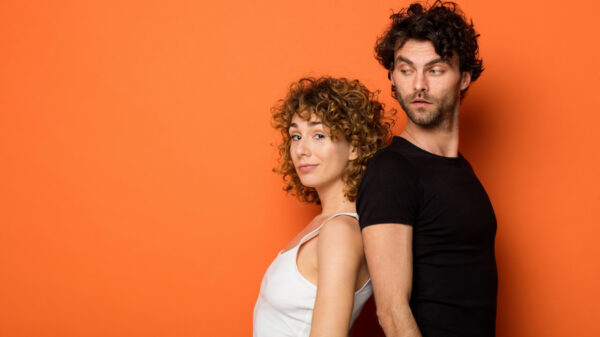 Casal jovem em um fundo laranja.