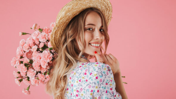 mulher de perfil sorrindo com um buquê de rosas na mão e fundo azul