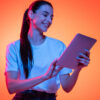 Retrato de uma mulher usando uma camiseta branca, isolada em fundo de cor laranja em luz neon.
