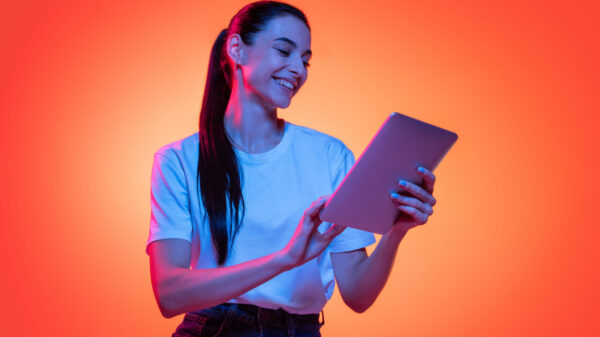 Retrato de uma mulher usando uma camiseta branca, isolada em fundo de cor laranja em luz neon.