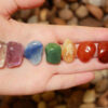 sete pedras dos chakras enfileiradas na palma de uma mão esquerda