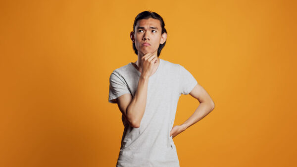 Homem pensando em algo, em um estúdio com o fundo laranja.