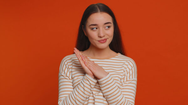 mulher de blusa listrada olhando para o lado com o canto do olho em fundo vermelho