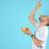 Homem comendo batatas chips em um fundo de cor azul.