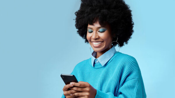 Mulher sorrindo, usando um celular, feliz.