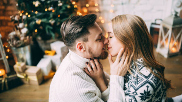 casal se beijando em uma sala com árvore de natal