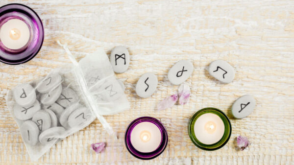 mesa com runas e três velas, sendo duas em vidro roxo e uma em vidro verde