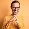 homem sorrindo vestindo laranja e em fundo laranja