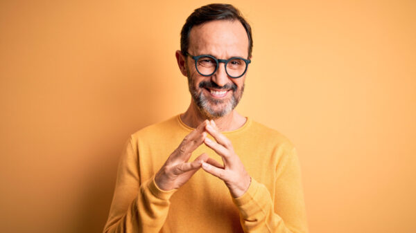 homem sorrindo vestindo laranja e em fundo laranja