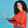 Mulher feliz usando um notebook, isolada em um fundo azul, sorrindo.