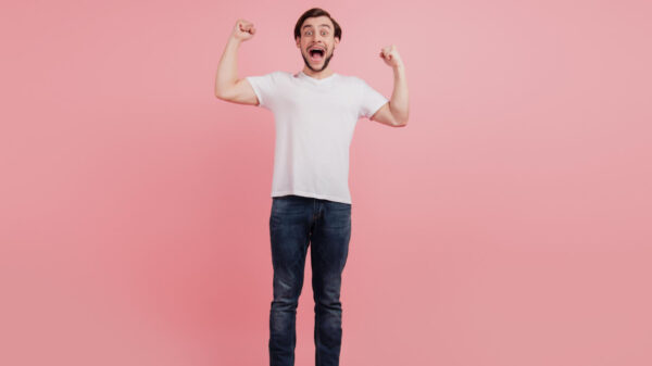 Foto em tamanho real de um homem alegre e sortudo comemorando, isolado sobre um fundo de cor rosa.