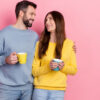 casal se abraçando e cada um segurando uma caneca em fundo rosa