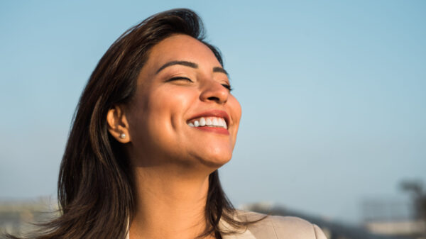 mulher de olhos fechados e sorrindo em um ambiente em céu aberto