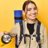 Mulher com uma mochila nas costas, segurando uma lanterna.