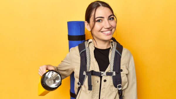 Mulher com uma mochila nas costas, segurando uma lanterna.