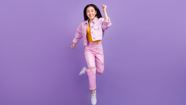 mulher com traços asiáticos com expressão de felicidade em fundo roxo