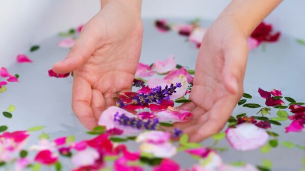 banheira branca com ervas e flores com um par de mãos dentro