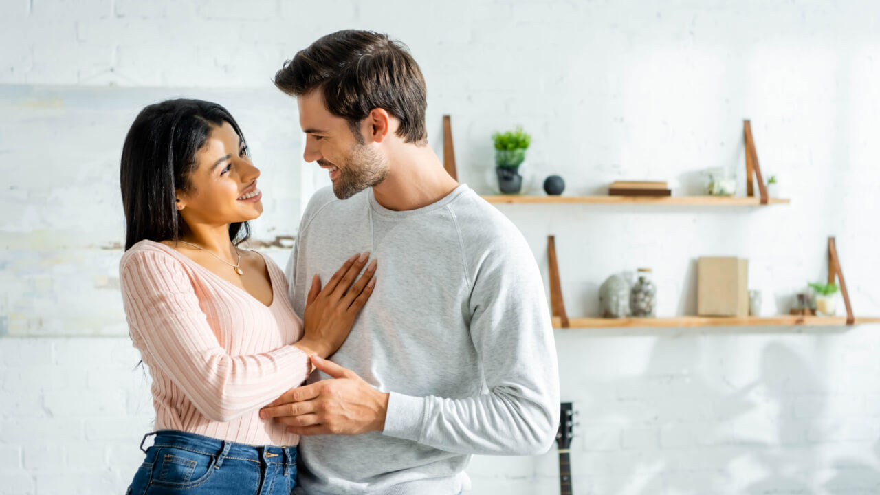 casal em um ambiente semelhante a cozinha de uma casa