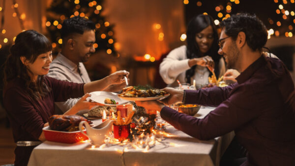 grupo e cinco amigos sentados em volta uma mesa reunidos celebrando a ceia em comemoração ao natal