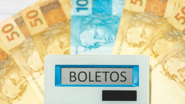 calculadora escrito boletos no visor e ao fundo notas de cinquenta com uma nota de cem reais ao meio