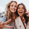 dupla de amigas felizes tirando foto a céu aberto
