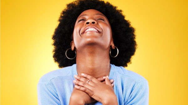 Mulher feliz, animada, em um fundo amarelo, com as mãos no peito, grata por sorte.