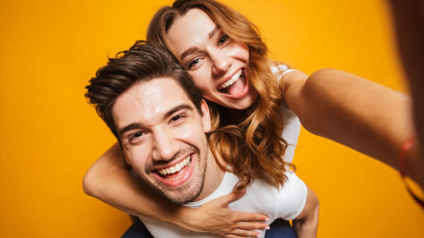casal hétero com ela montada nas costas dele em fundo amarelo