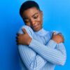 Mulher vestindo roupas casuais, abraçando-se, feliz e positiva, sorrindo, autoconfiante. Conceito de amor próprio e autocuidado.