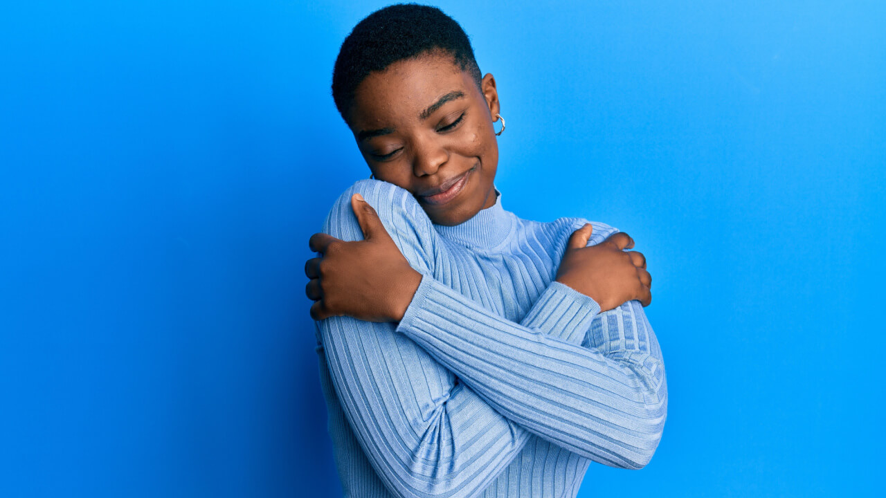 Mulher vestindo roupas casuais, abraçando-se, feliz e positiva, sorrindo, autoconfiante. Conceito de amor próprio e autocuidado.