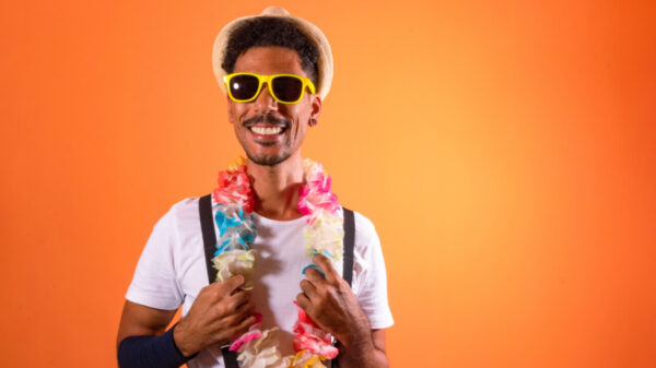 Homem usando uma fantasia de carnaval, se divertindo, isolado em um fundo laranja.