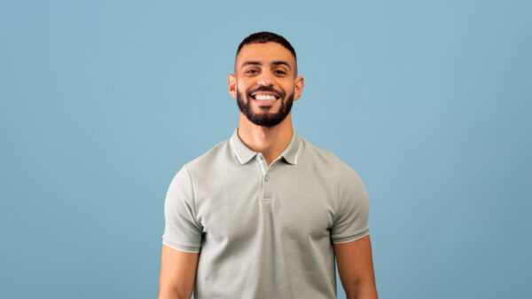 ao centro da imagem está um homem com barba e sorrindo em fundo azul