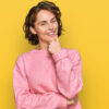 Mulher usando roupas casuais, parecendo confiante, olhando para a câmera, sorrindo, com os braços cruzados e uma mão no queixo, pensando positivo.
