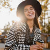 mulher sorrindo em um parque aberto e com o sol forte na fotografia