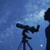 Astrônomo com um telescópio observando as estrelas e a lua.
