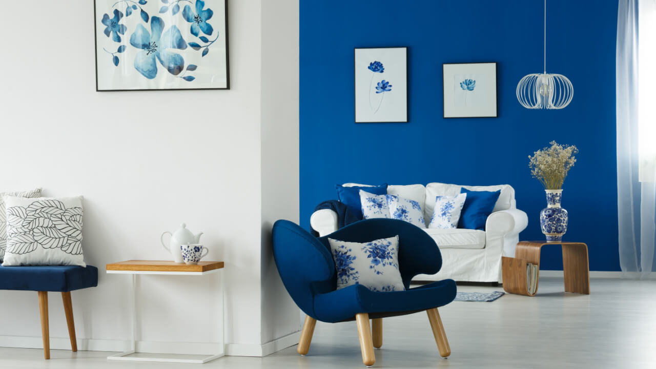 foto de uma sala com a parede da esquerda branca e a parede da direita azul escuro e as decorações também na cor azul