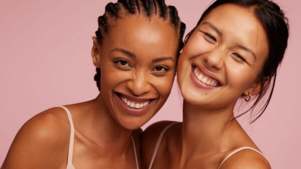 duas mulheres se abraçando e sorrindo em fundo rosa