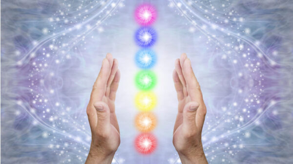 Mãos paralelas masculinas com 7 centros de energia coloridos em um fundo azul brilhante.
