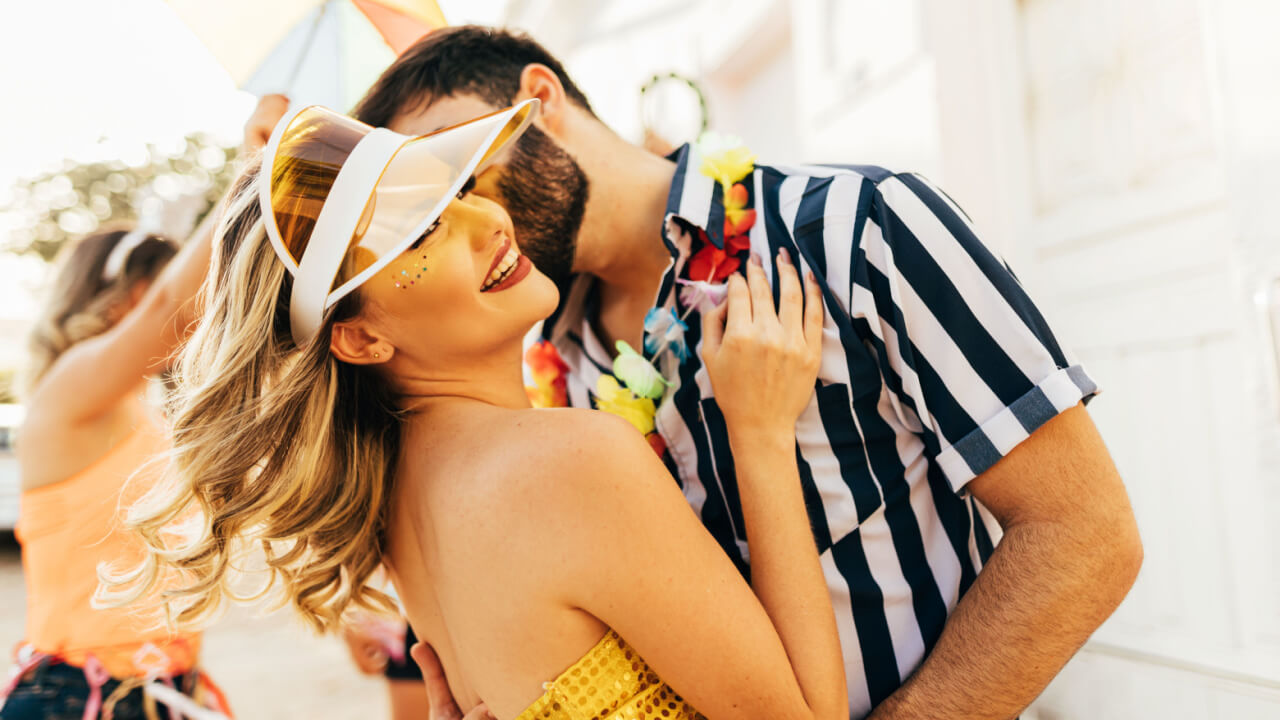 homem beijando o rosto de uma mulher e ambos estão fantasiados para o carnaval