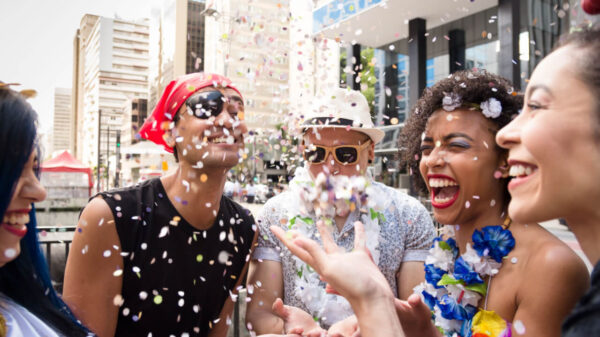 grupo de quatro amigos fantasiados para o carnaval e jogando confetes