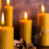 no primeiro plano há uma vela amarela acesso e no plano de fundo fundo três quatro velas amarelas acesas