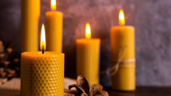 no primeiro plano há uma vela amarela acesso e no plano de fundo fundo três quatro velas amarelas acesas