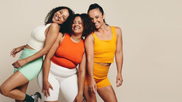mais à esquerda da imagem há três mulheres negras com roupa de academia em um fundo acinzentado