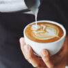 Xícara de café com um desenho sendo feito com creme.
