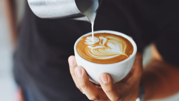 Xícara de café com um desenho sendo feito com creme.