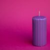 imagem de uma vela roxa à direita em um fundo também roxo