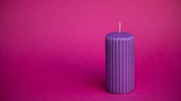 imagem de uma vela roxa à direita em um fundo também roxo